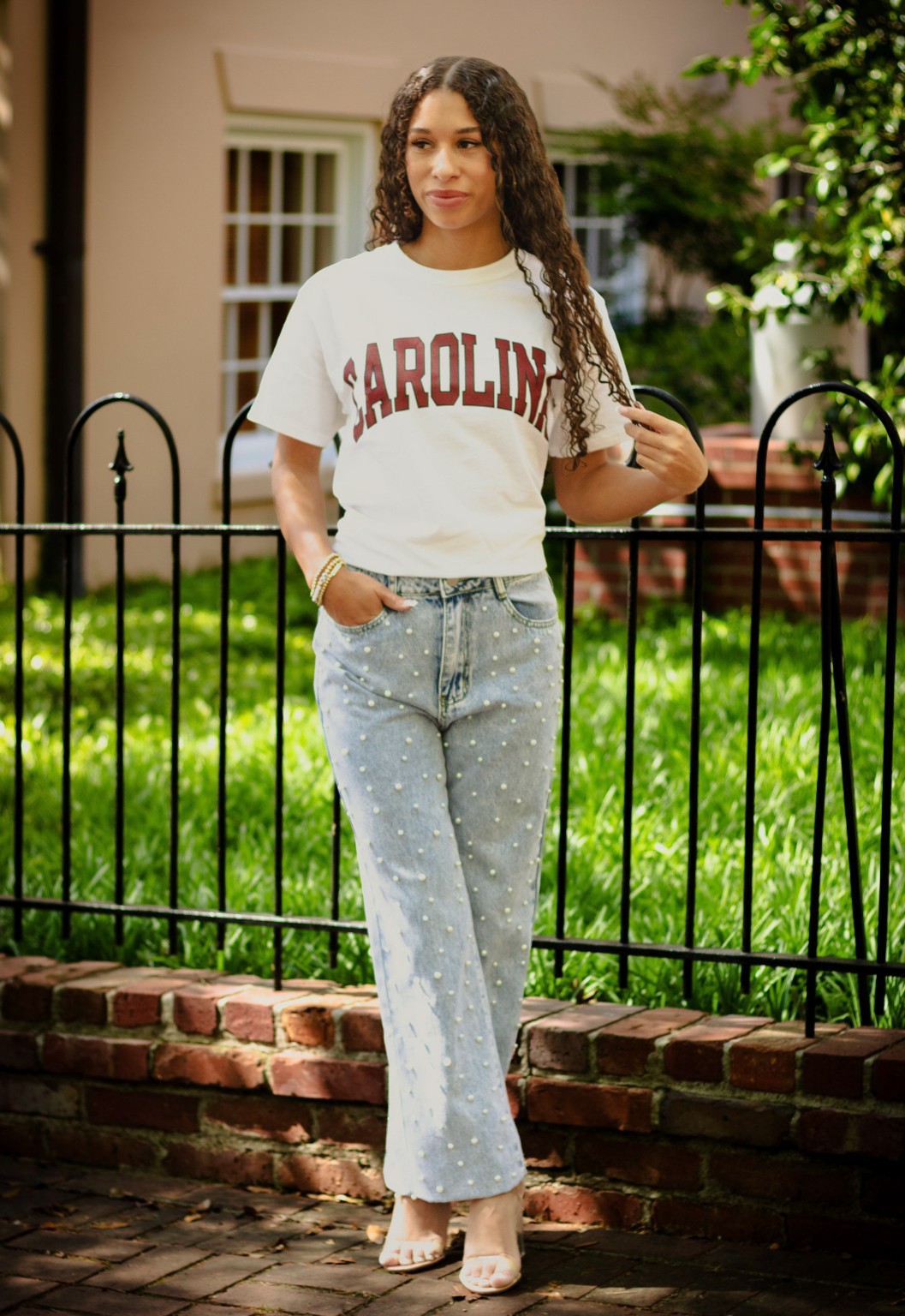 Layla in her Carolina shirt beside a garden fence