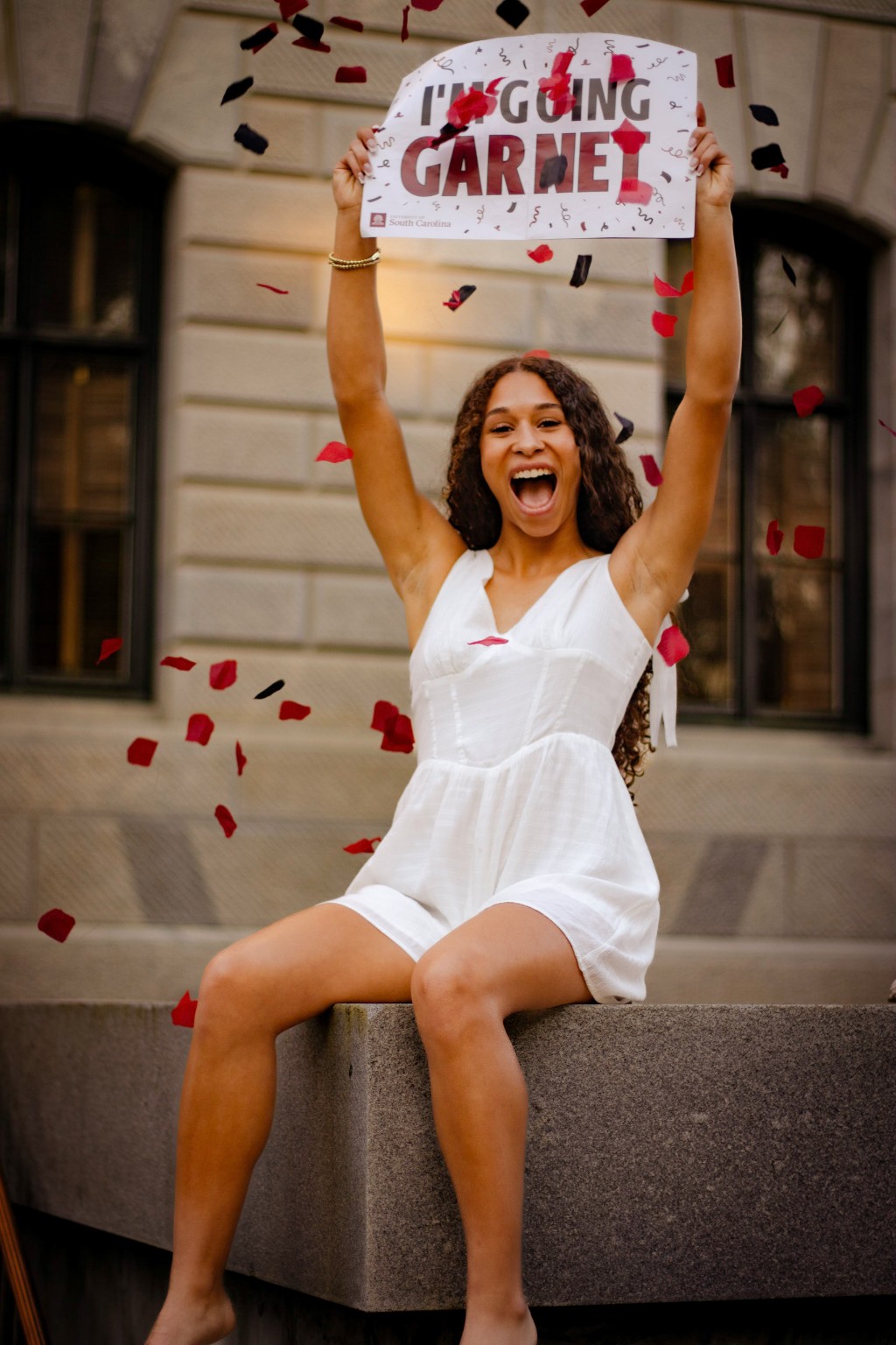 Layla celebrating with an I'm Going Garnet sign and falling confetti
