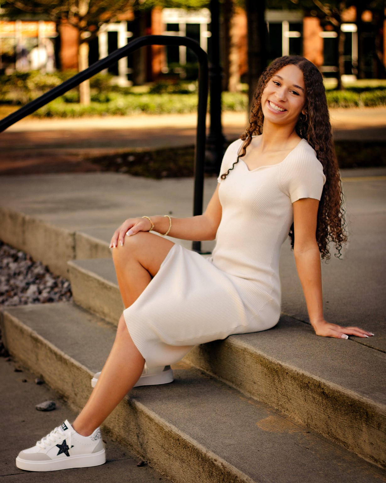 Layla seated outdoors in a white dress