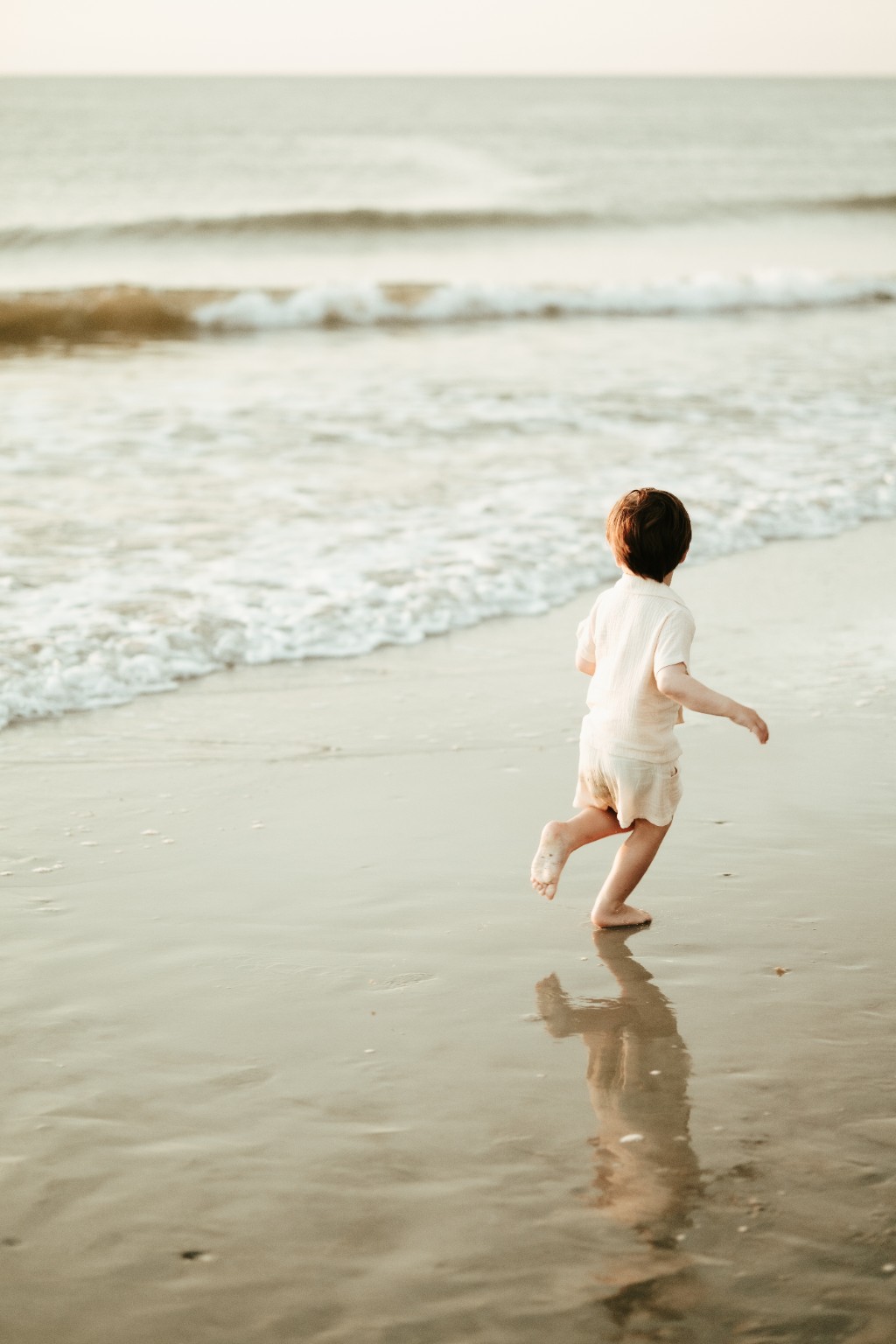 A young boy running toward the ocean