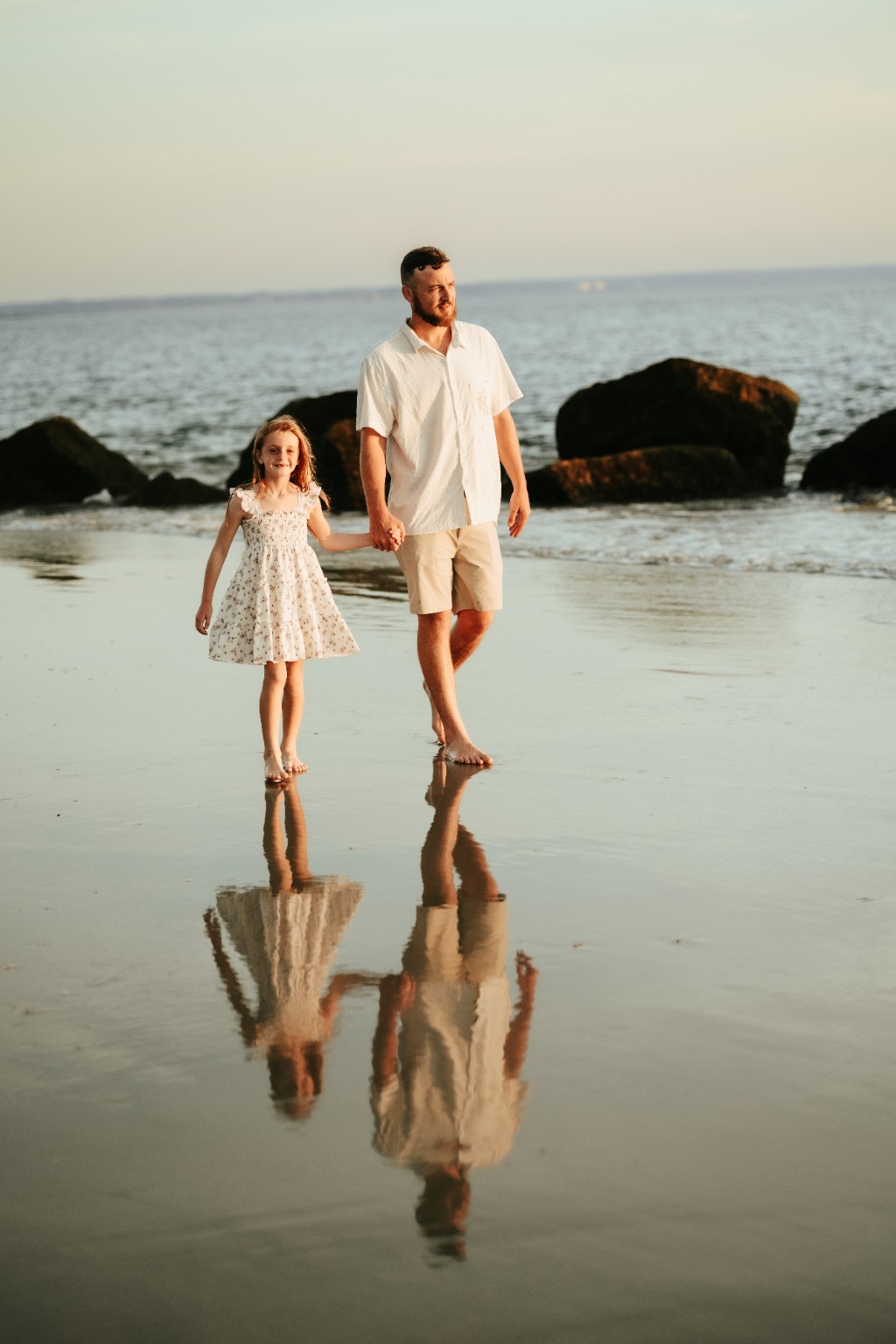 A father and daughter walking hand in hand along the beach